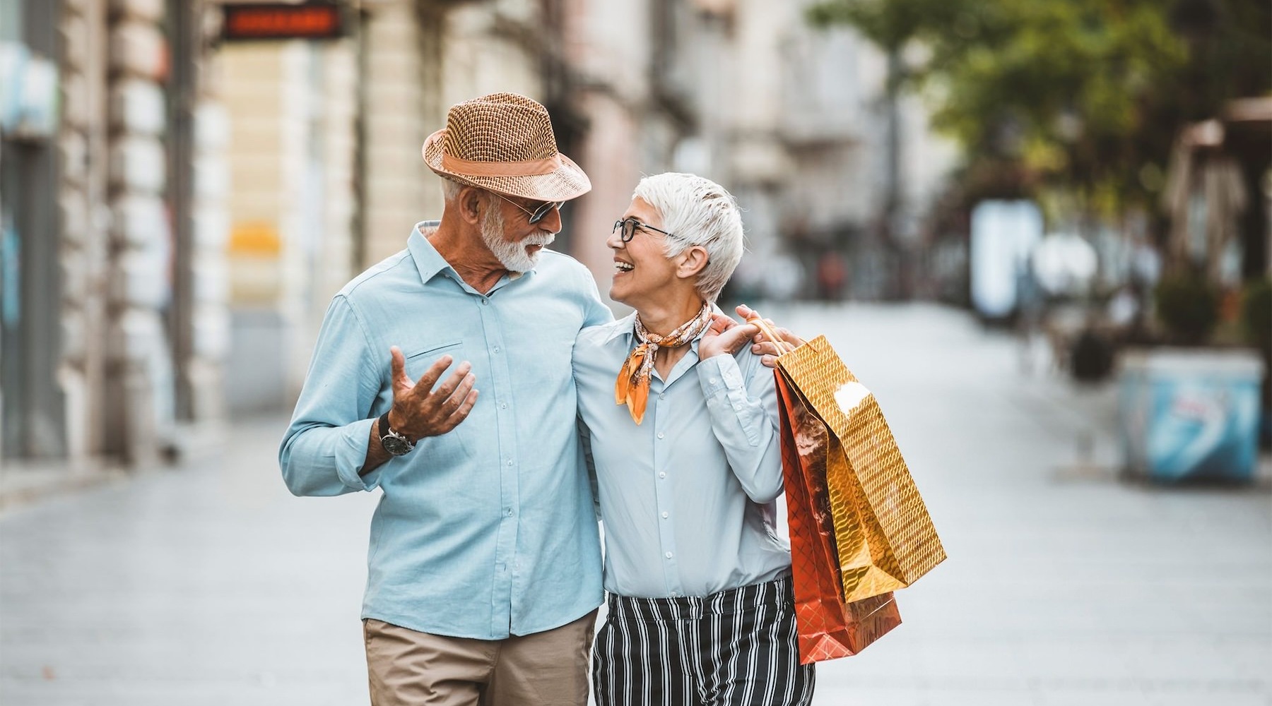 a man and woman holding shopping bags while walking